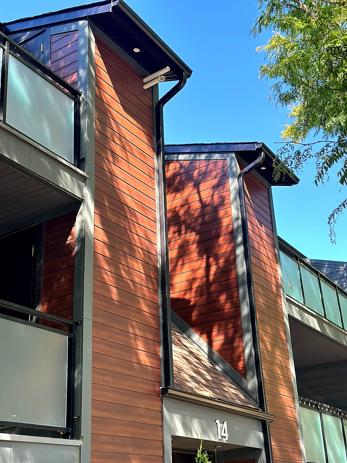 Wood-look composite cladding paired with black metal and glass balconies