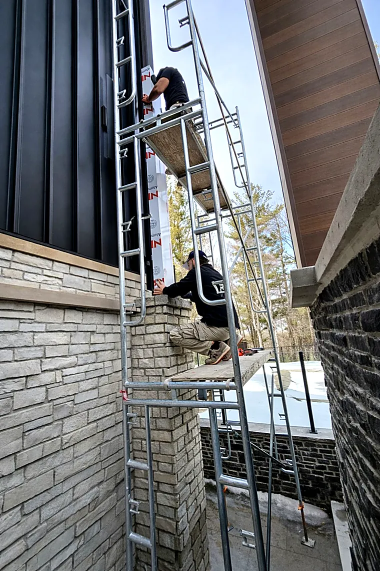 Installers on scaffolding fitting black metal panels