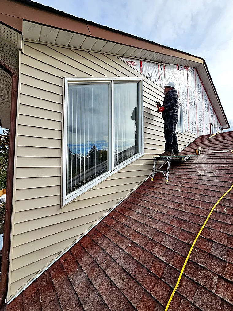 Installer fitting siding on an upper gable wall